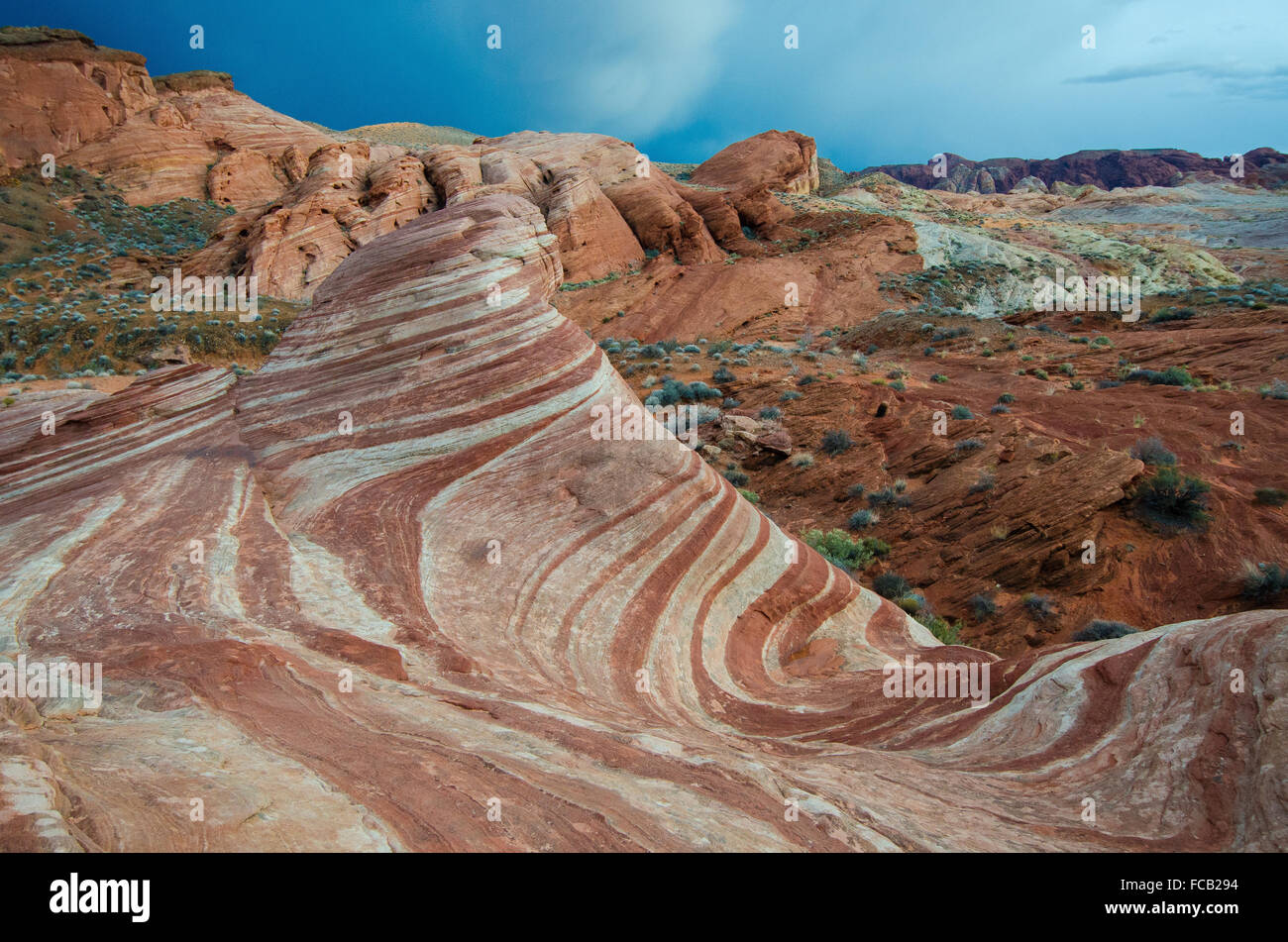 Dark ominous clouds glide past the swirling red rock striations of Valley of Fire State Park. Stock Photo