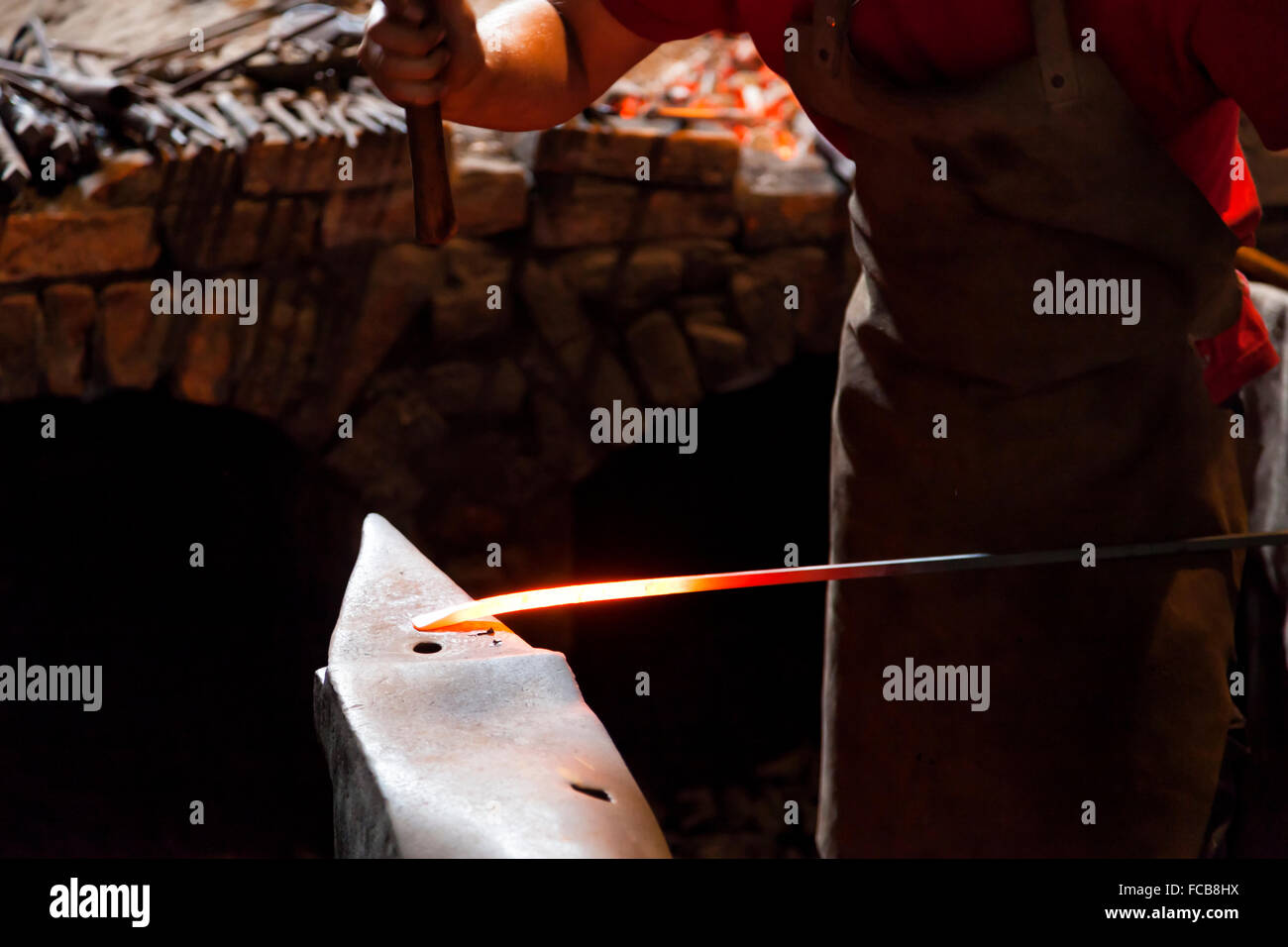 Blacksmith forging steel with hammer and anvil Stock Photo