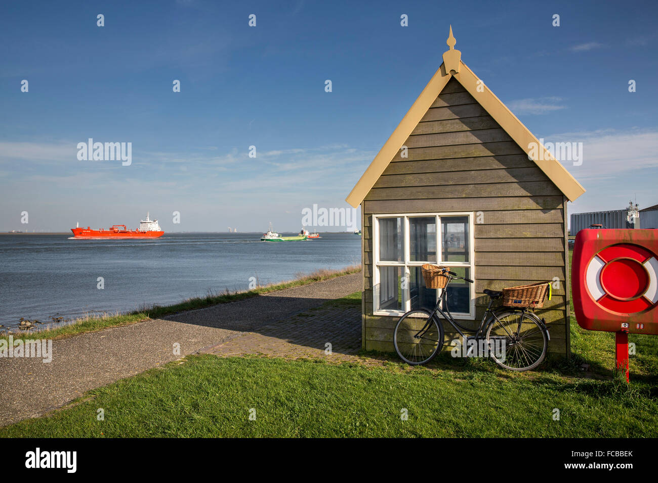 Netherlands, Walsoorden, Westerschelde river. Cargo ships, bicycle Stock Photo