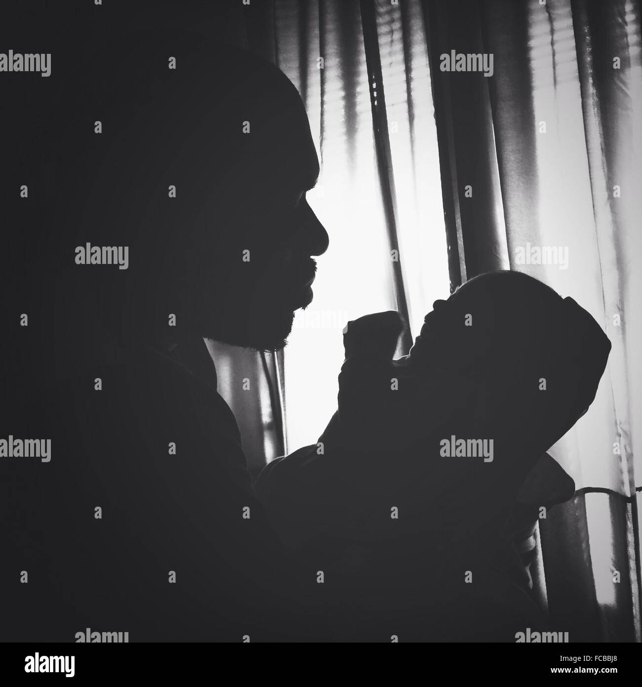 Side View Of Silhouette Man Holding Baby Stock Photo