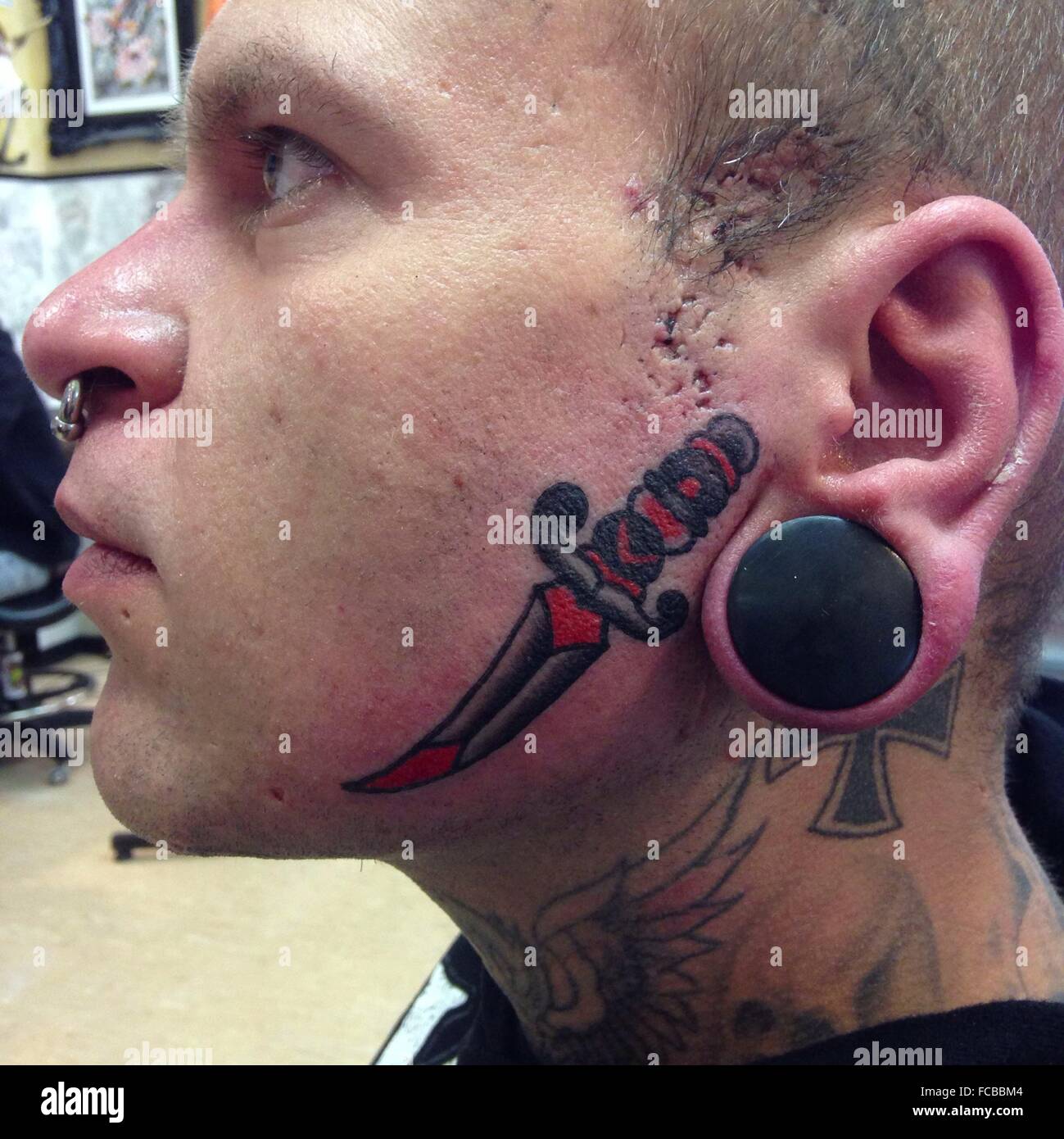 Side View Of Man With Tattoo On Face And Earplugs Stock Photo