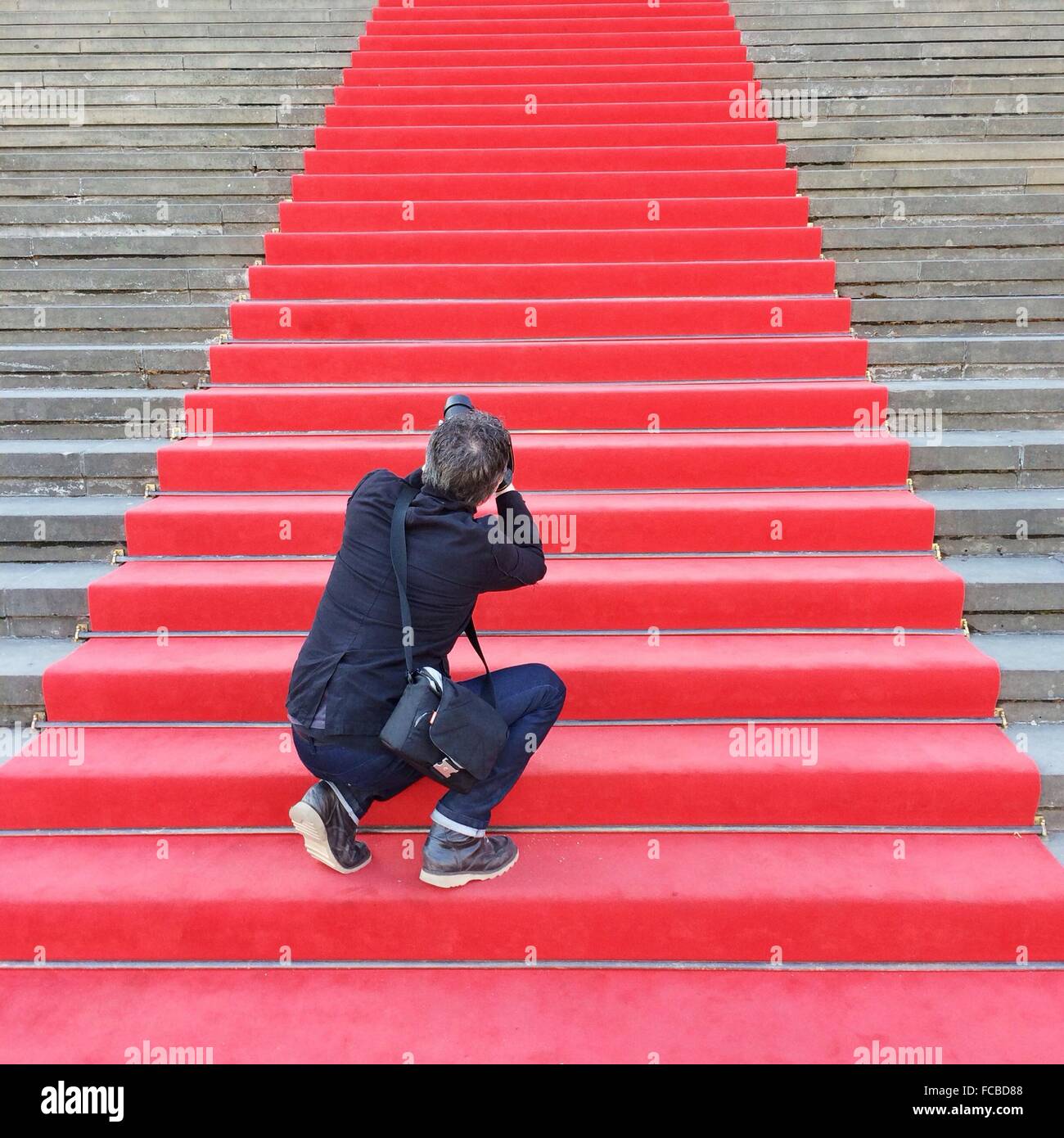 Rear View Of A Male Paparazzi On Red Carpeted Stairs Stock Photo