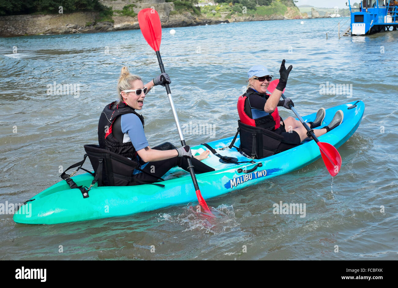 Daughter and mother n a kayak waving off to sea Stock Photo