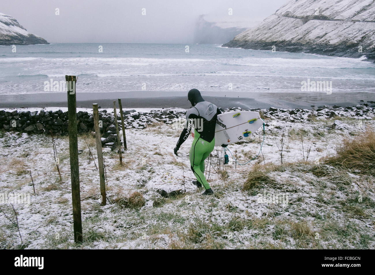 Pro surfer Indar Unanue on his way to the water in the Faroe Islands Stock Photo