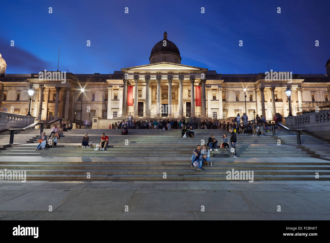 The National Gallery at Trafalgar Square in London in the evening, tourists on the stairway Stock Photo