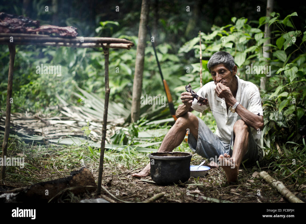 Shaman and hunter in Amazon forest  eating wild meat ,Iquitos, Peru Stock Photo