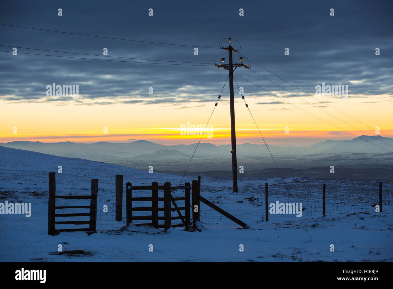 Looking towards the Lake District hills from Hartside in the North Pennines at sunset with an electricity pylon. Stock Photo