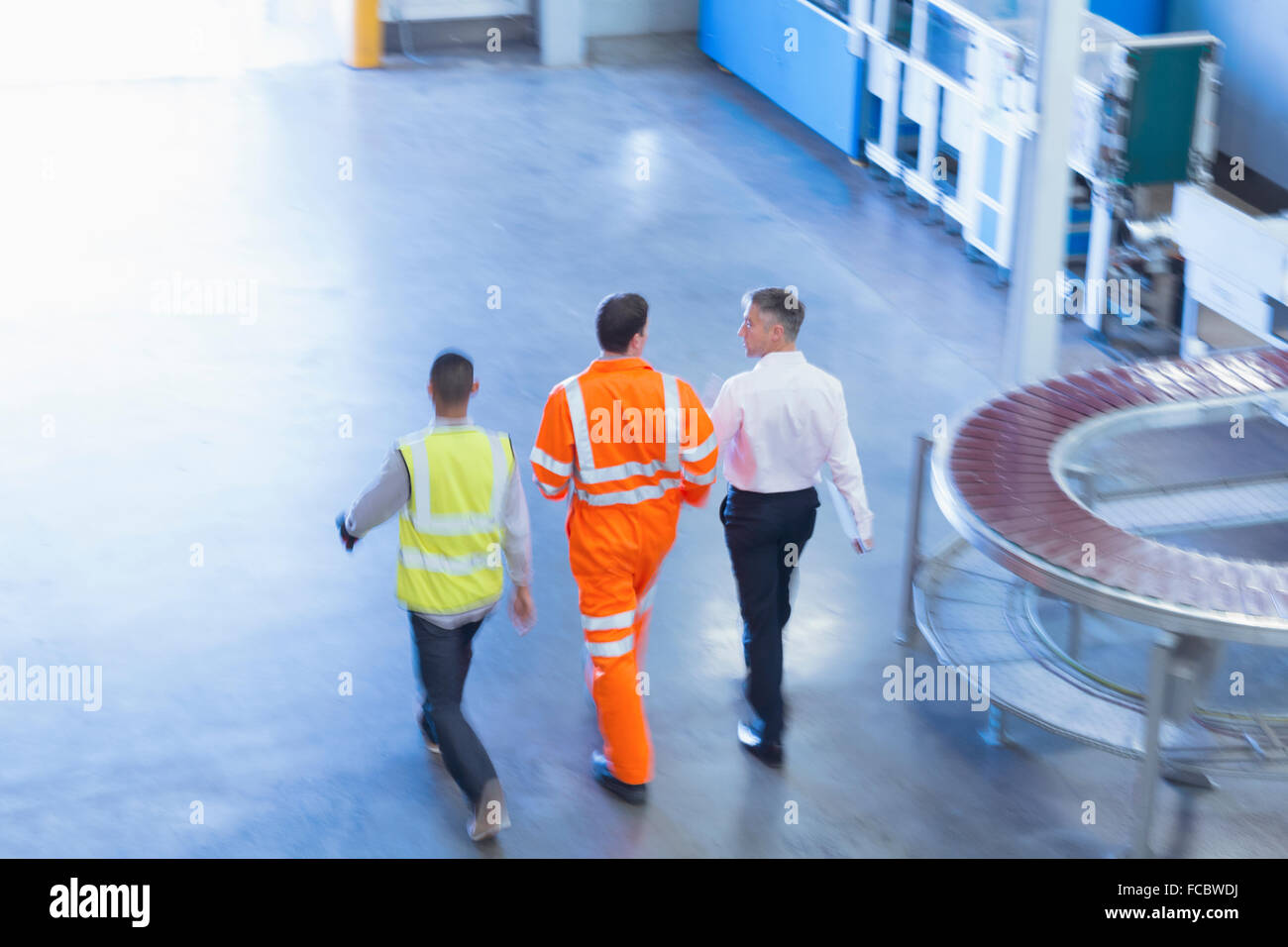 Workers in reflective clothing walking in factory Stock Photo