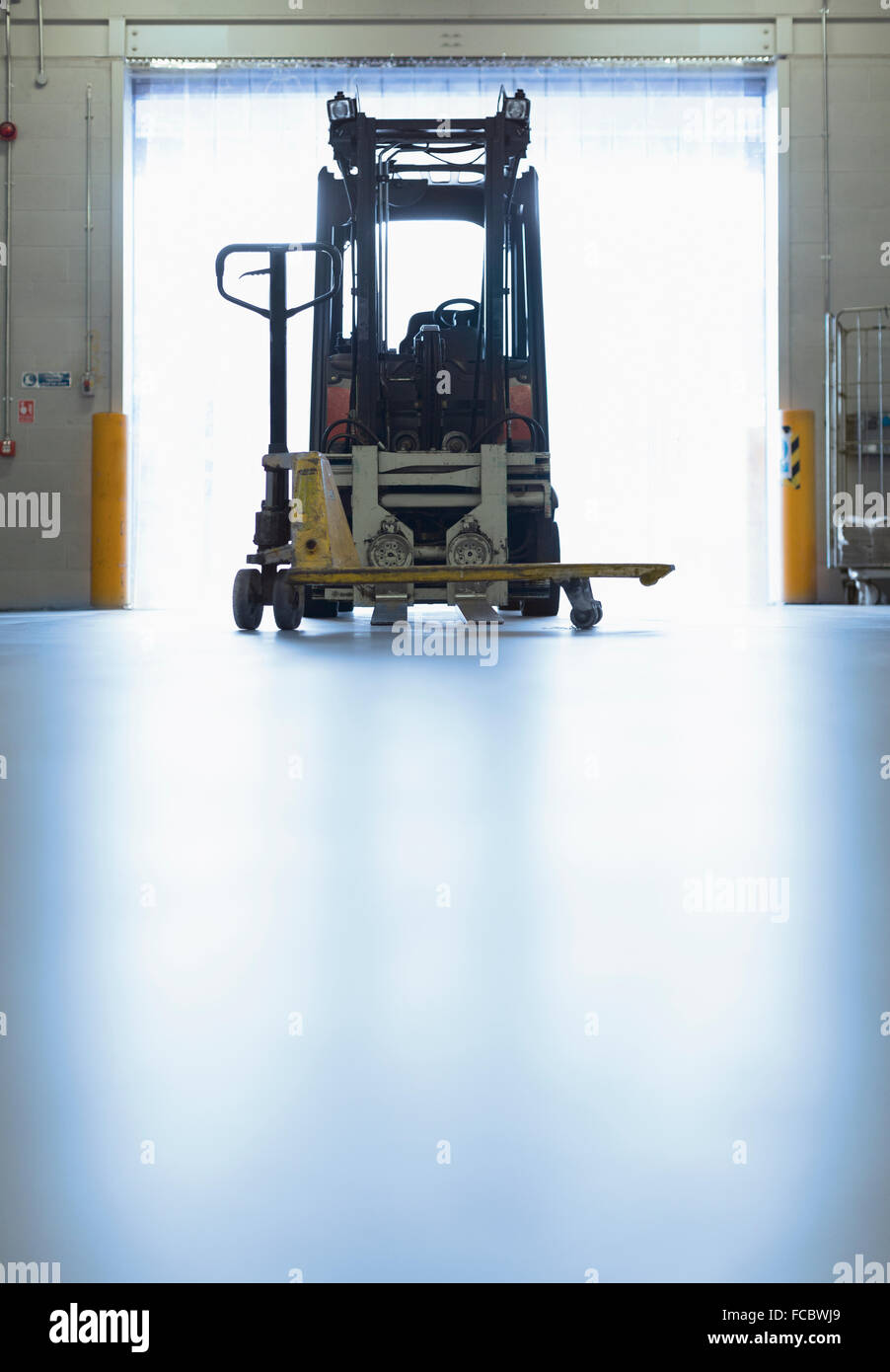 Forklift parked in warehouse loading dock doorway Stock Photo