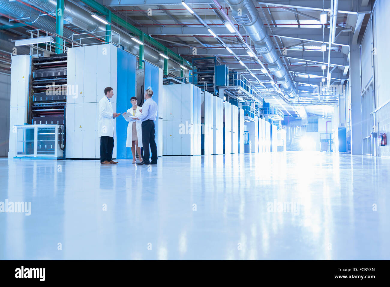 Scientists and businessman talking in factory Stock Photo