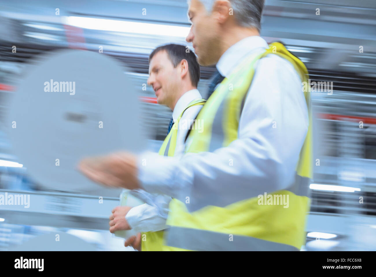 Workers in reflective clothing walking in factory Stock Photo