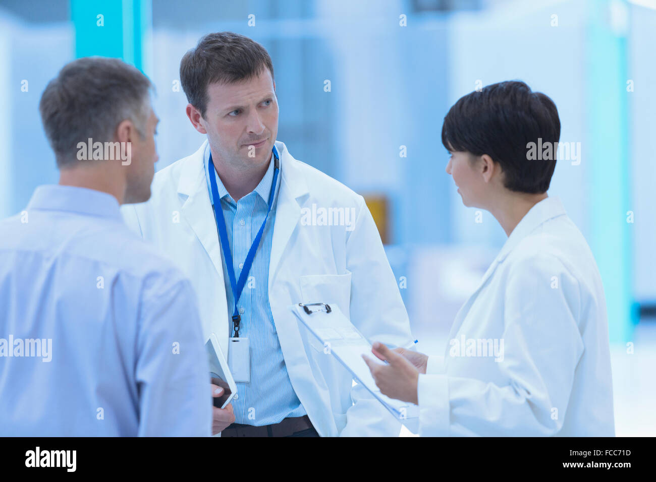 Scientists and businessman talking in factory Stock Photo