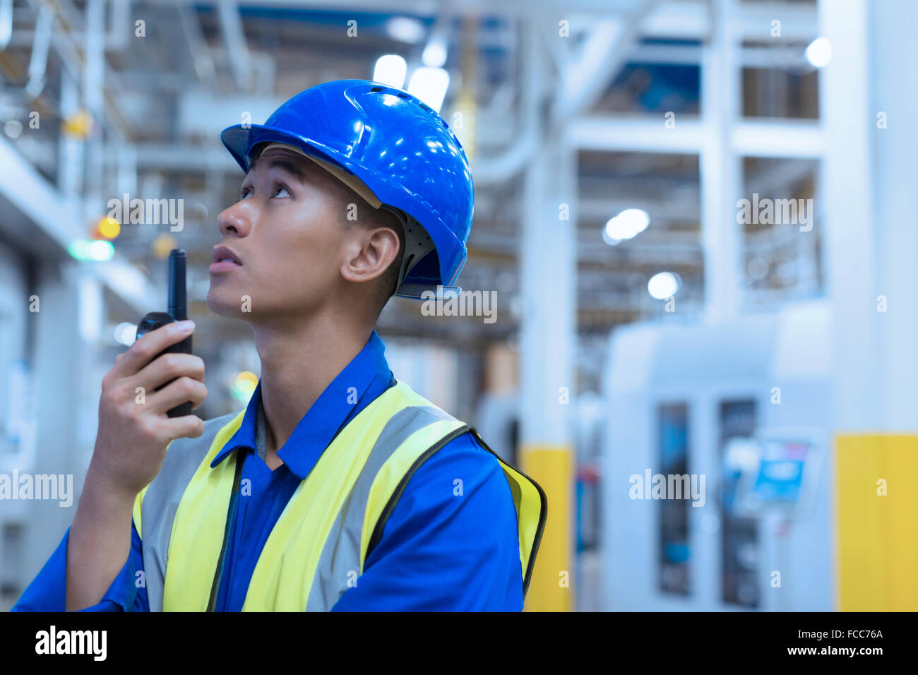 Worker in hard-hat using walkie-talkie in factory Stock Photo