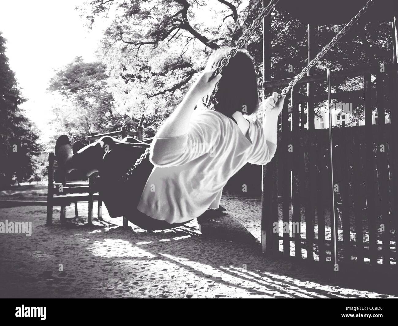 Rear View Of A Girl Sitting On Swing Stock Photo