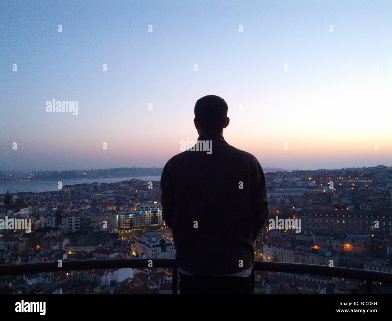 Man Overlooking City At Dusk Stock Photo
