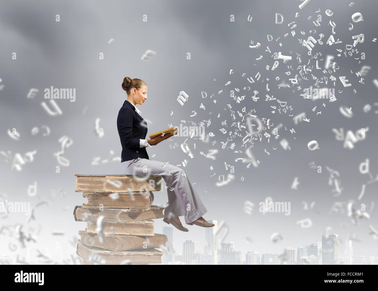 Young attractive woman sitting on pile of books and reading Stock Photo ...