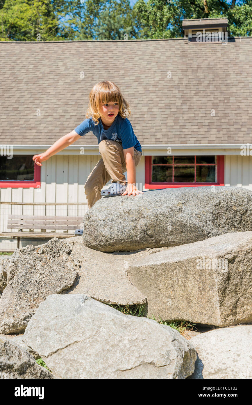Young boy climbing on rock pile Stock Photo - Alamy