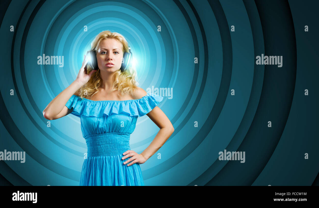 Young lady in blue dress with headphones enjoying the music Stock Photo