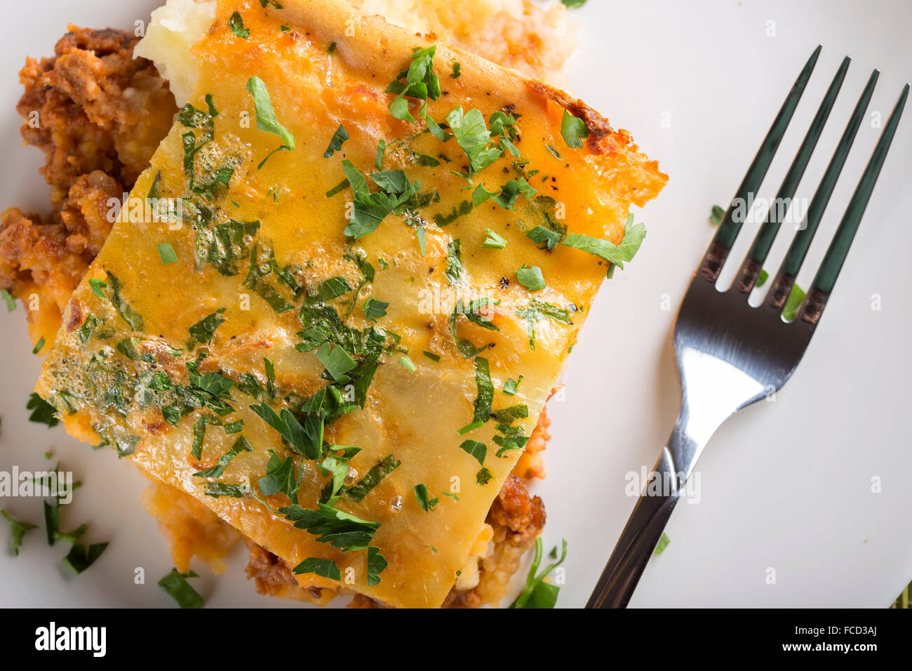 Moussaka with minced meat, potatoes and parsley on white plate Stock Photo