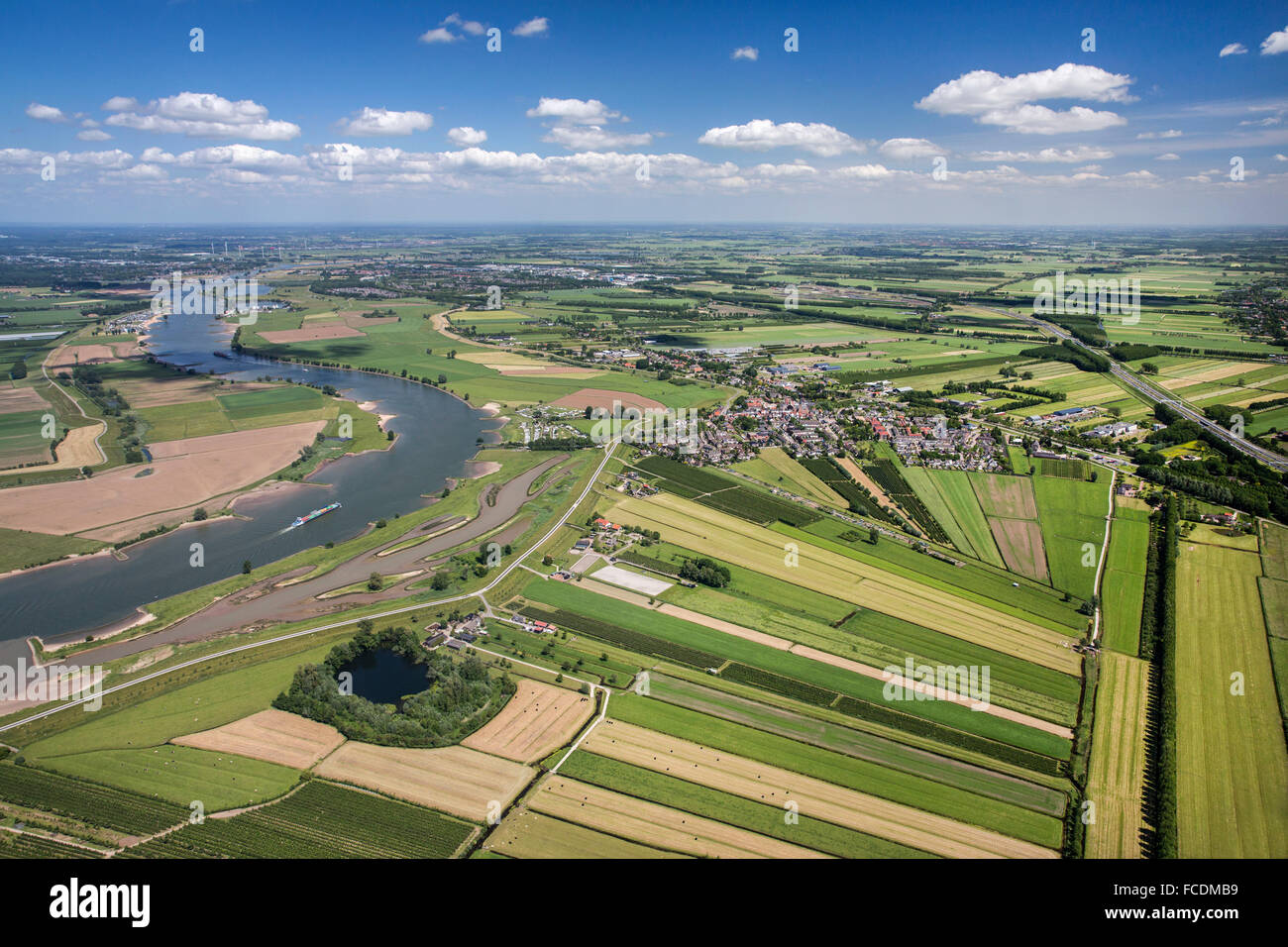 Netherlands, Lexmond, Cargo boat in river Lek. Farmland. Aerial Stock Photo