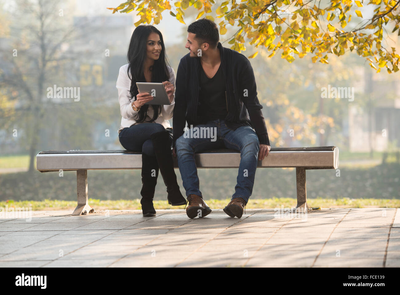 Beautiful Young Couple Sitting On Bench In The Park On A Beautiful ...