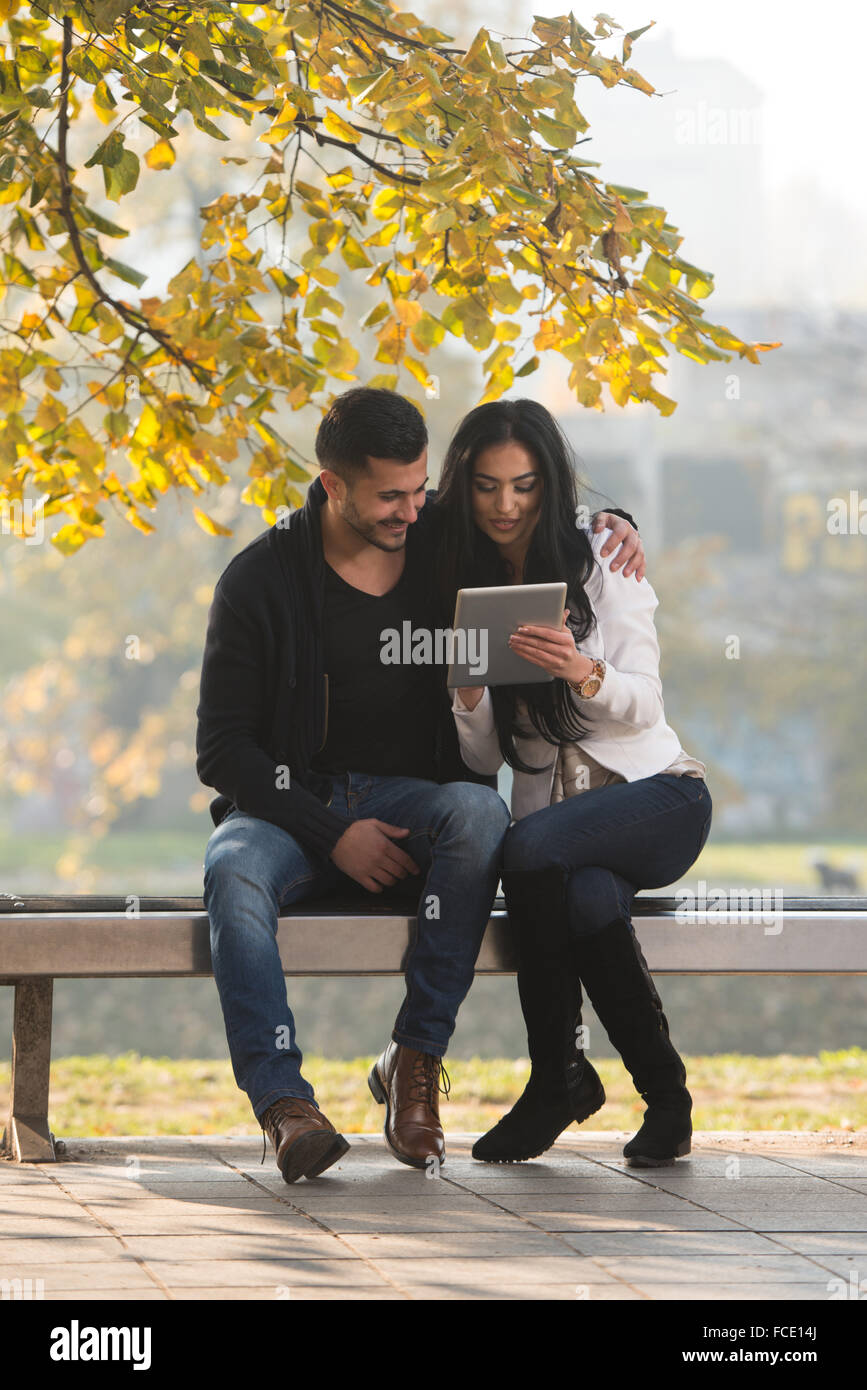 Beautiful Young Couple Sitting On Bench In The Park On A Beautiful ...