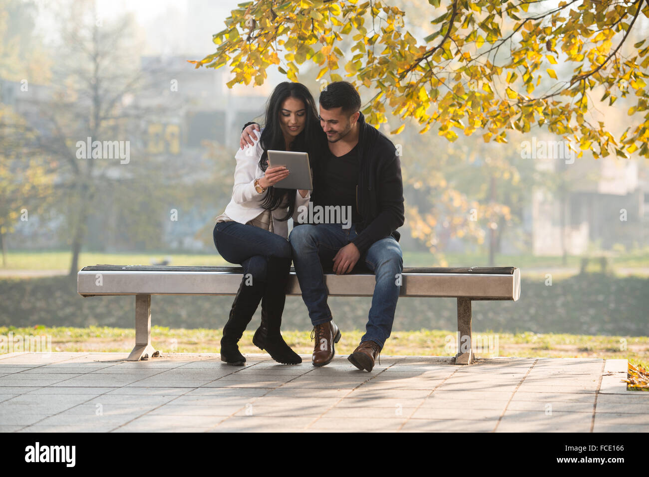 Beautiful Young Couple Sitting On Bench In The Park On A Beautiful ...