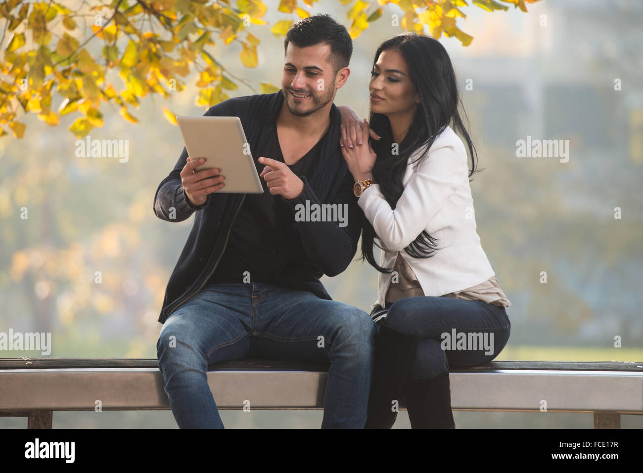 Beautiful Young Couple Sitting On Bench In The Park On A Beautiful ...