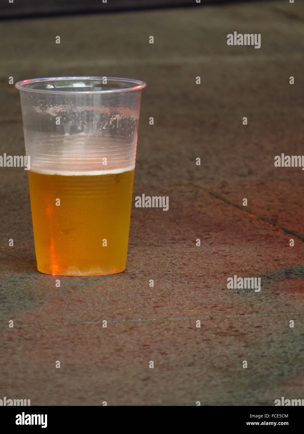 Beer In Plastic Glass On Floor Stock Photo