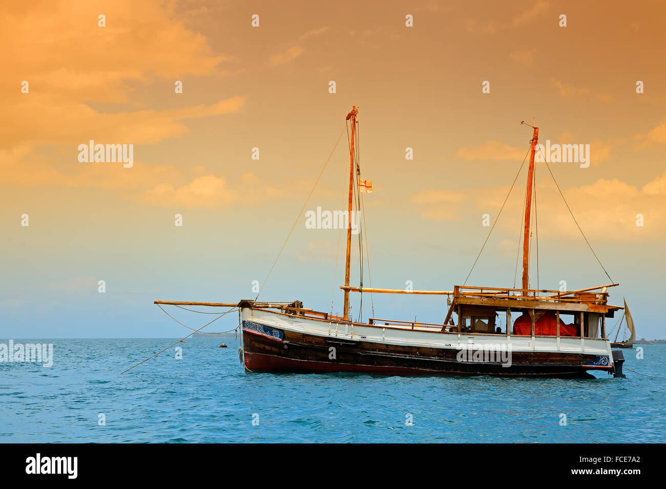 Wooden boat floating on the clear turquoise water of Zanzibar island Stock Photo
