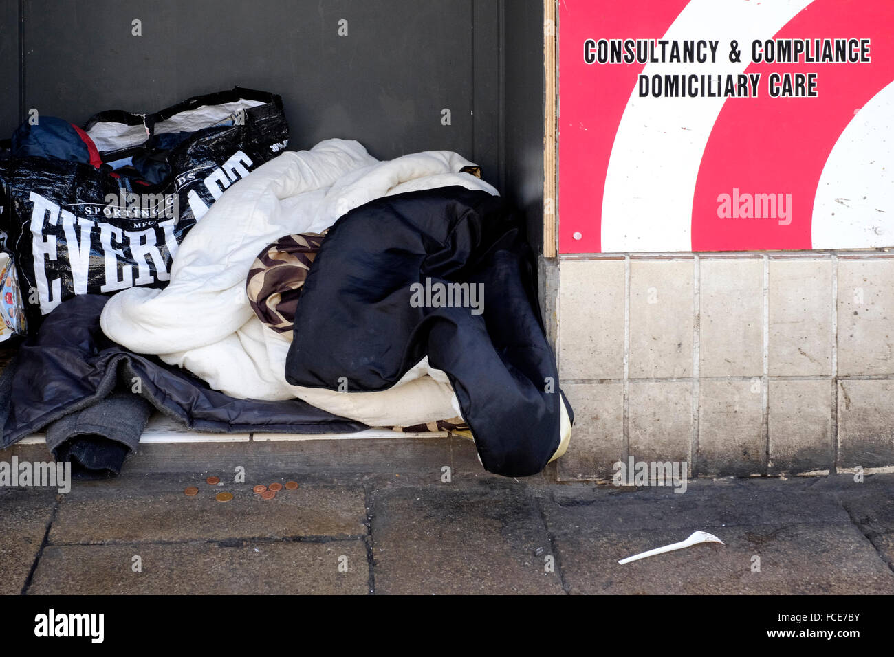 sleeping bags and blankets of homeless people stake out there patch in an empty closed shop doorway england uk Stock Photo