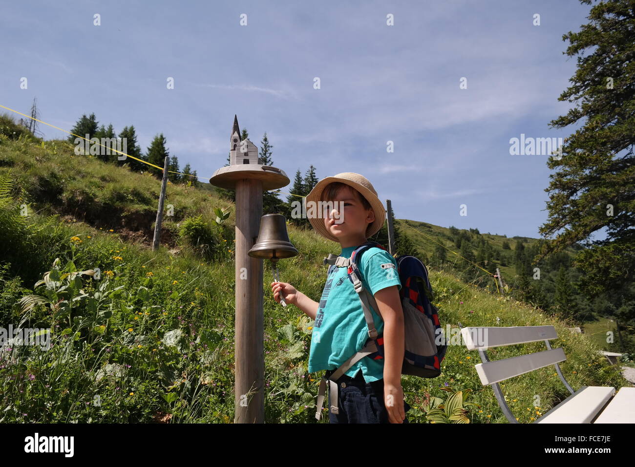 Boy With Back Pack Ringing Bell On Landscape Stock Photo