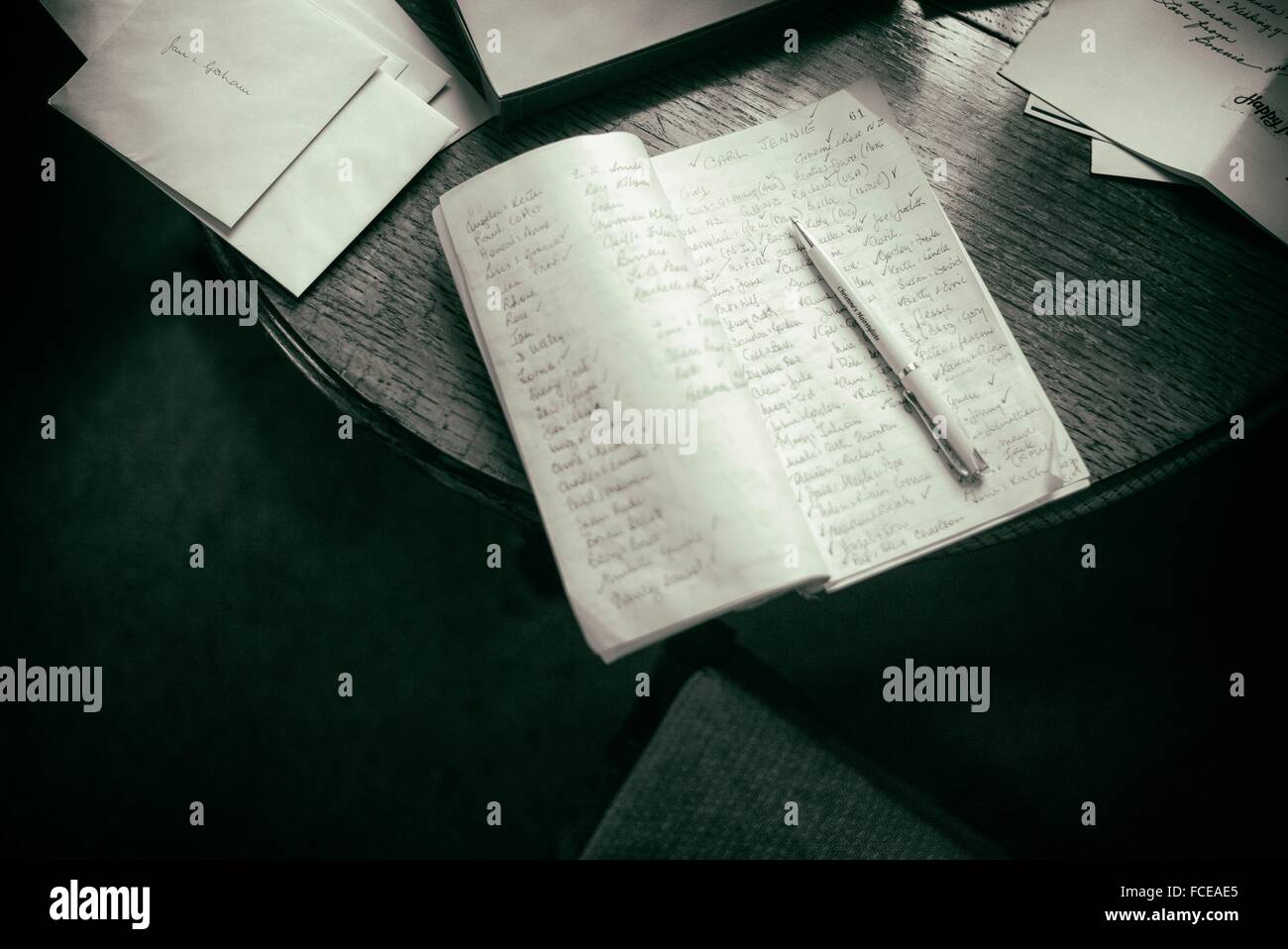 Notebook with handwritten names and a pen over a table with other papers and letters Stock Photo