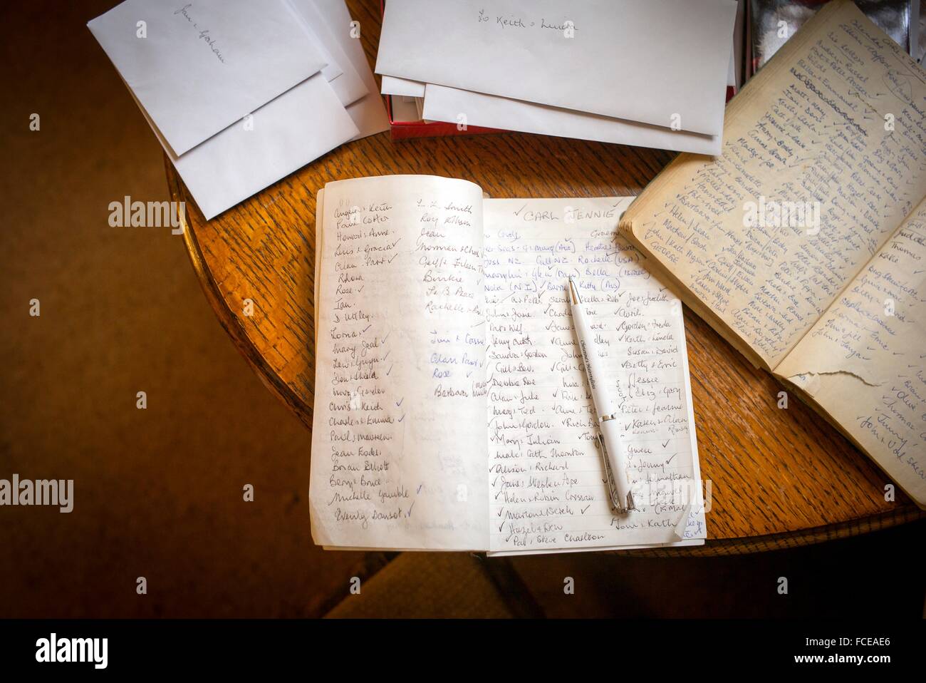 Notebooks with handwritten names and a pen over a table with other papers and letters Stock