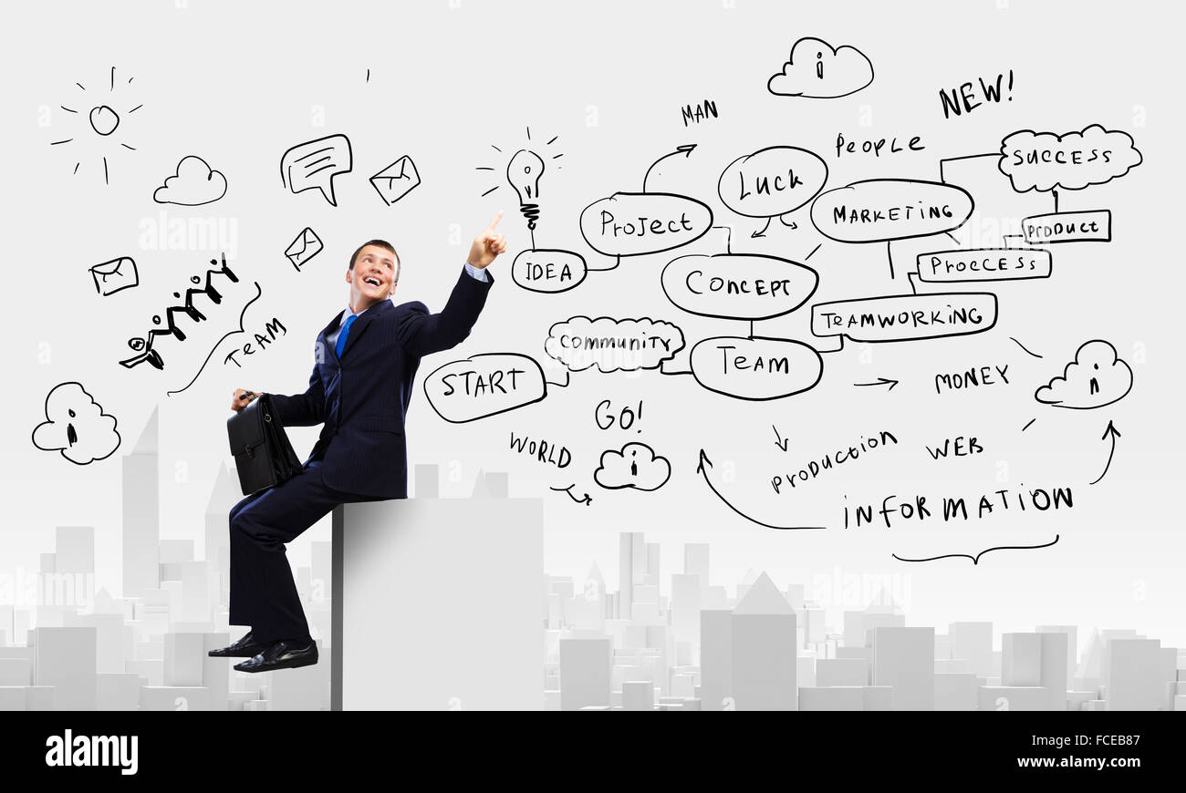 Young businessman with suitcase sitting on roof of building Stock Photo ...