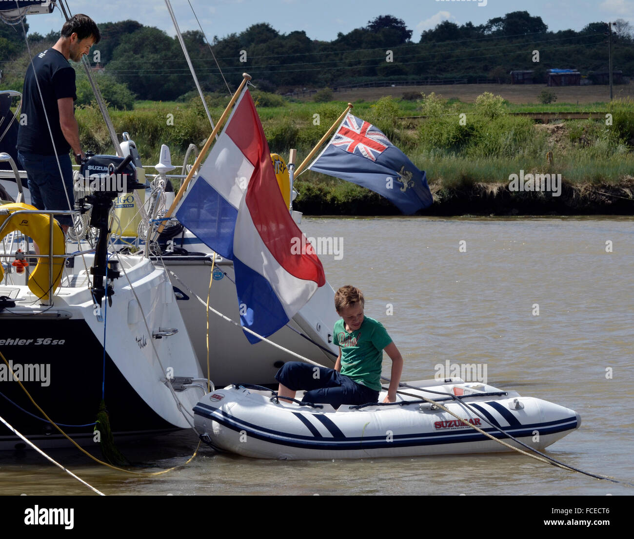 father watches son into inflatable tinghy tender at southwold Stock Photo
