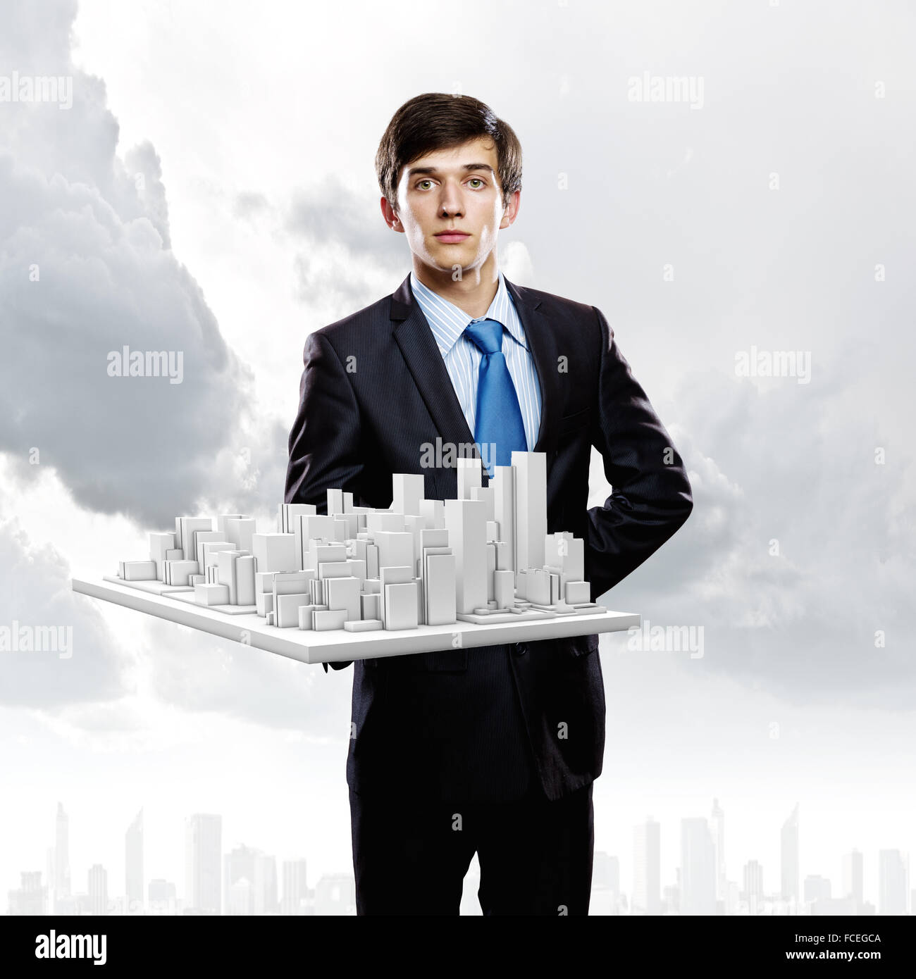 Handsome businessman holding model of modern city Stock Photo - Alamy