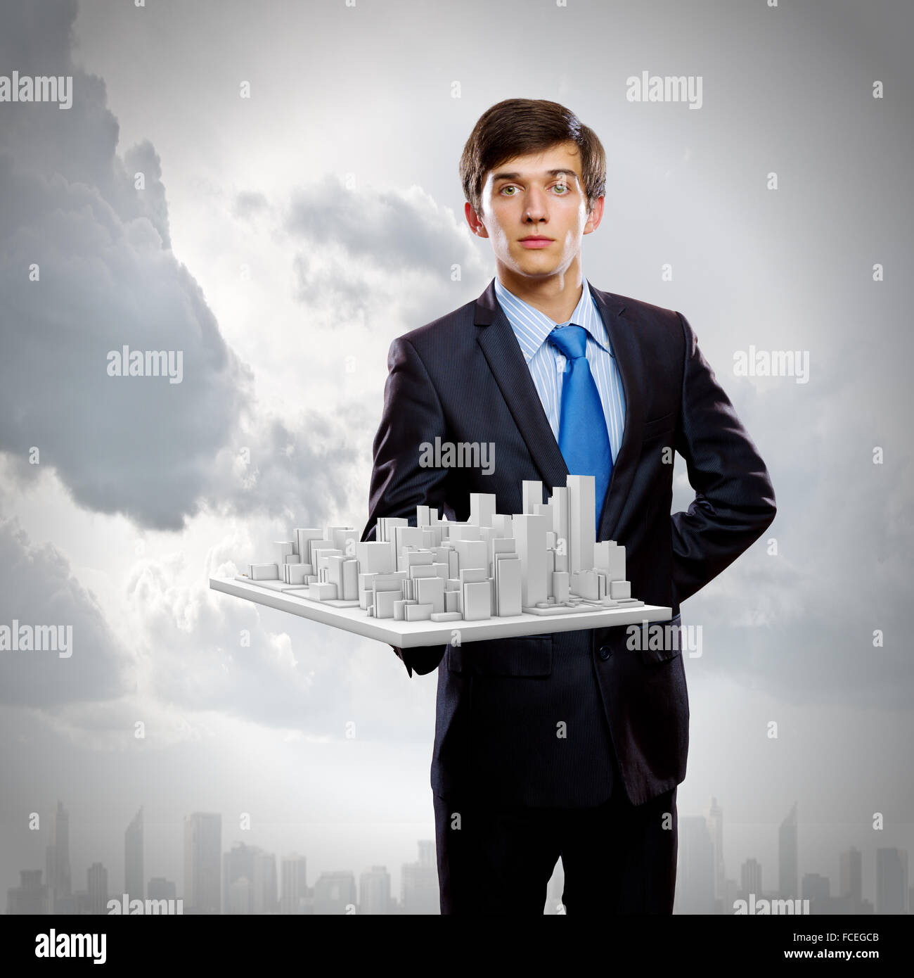 Handsome businessman holding model of modern city Stock Photo - Alamy