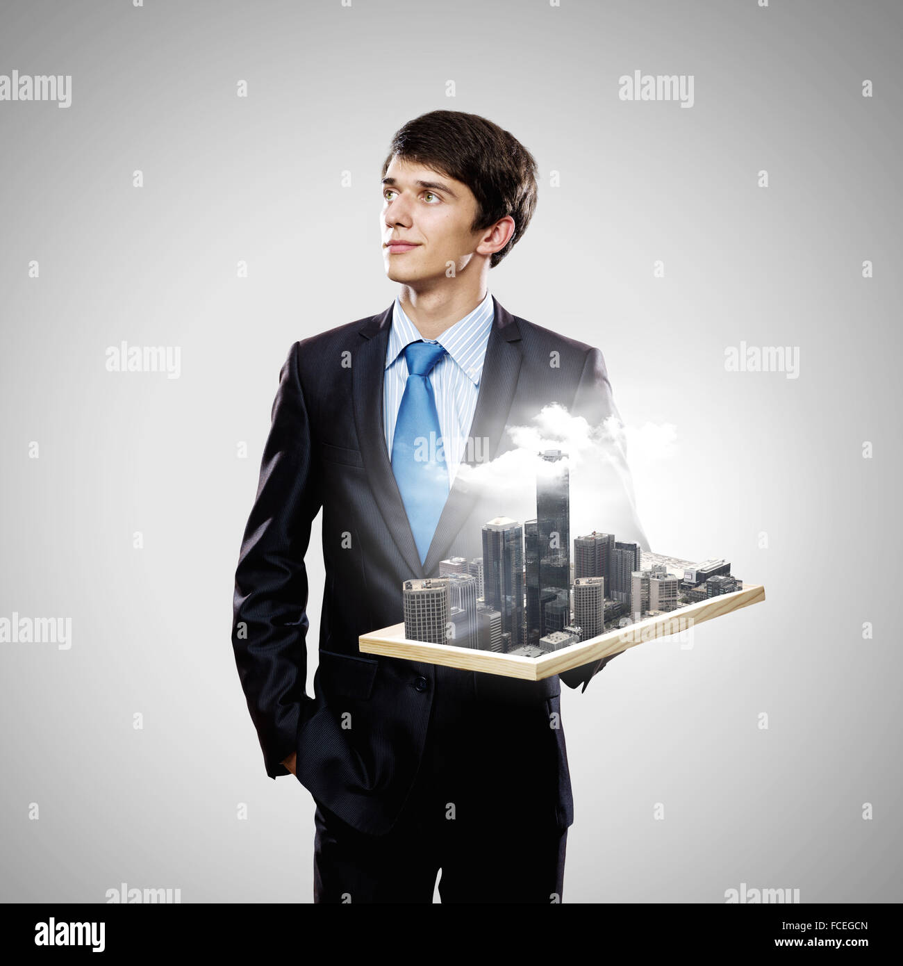 Handsome businessman holding model of modern city Stock Photo - Alamy