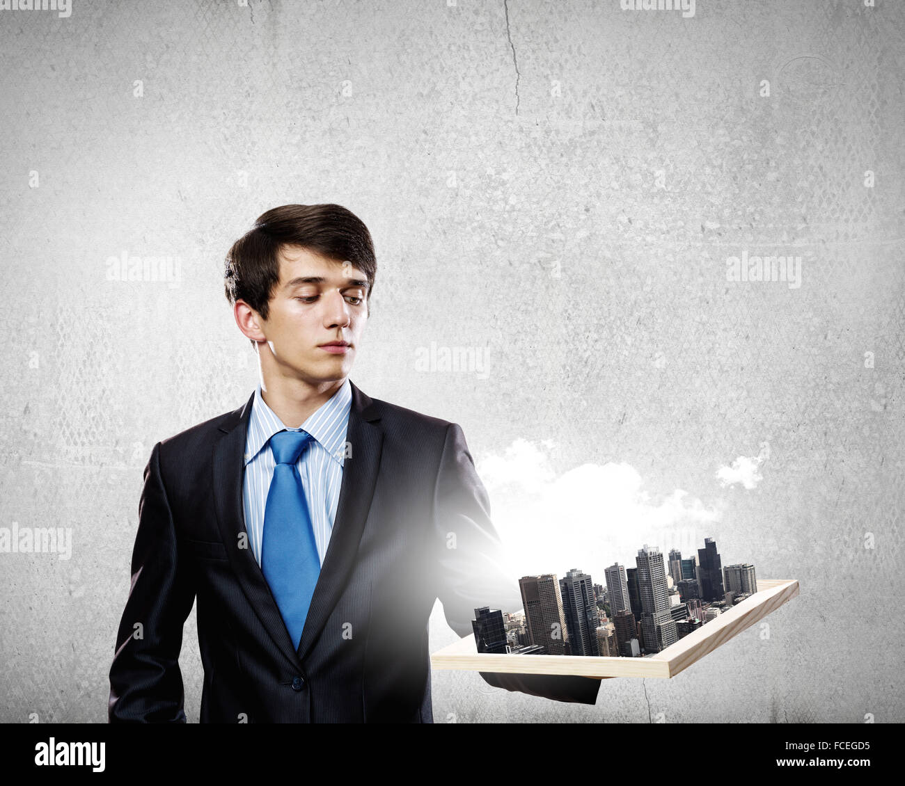 Handsome businessman holding model of modern city Stock Photo - Alamy