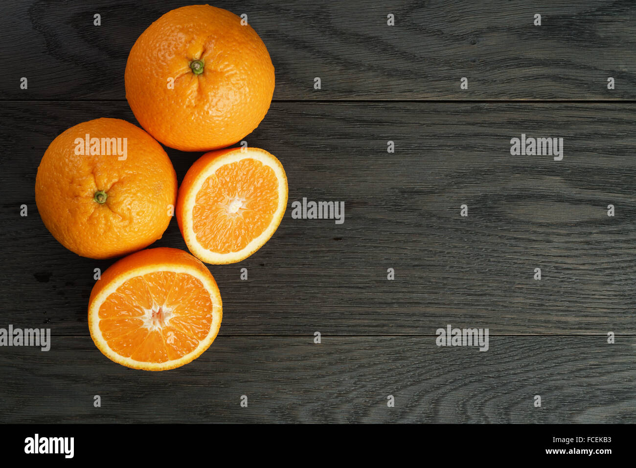 three ripe oranges on wooden table one half cut shot from above Stock Photo
