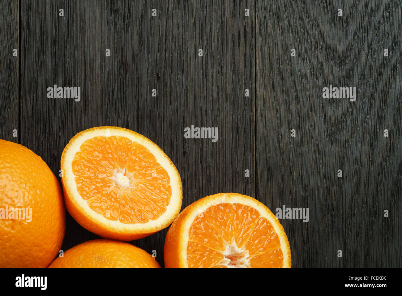 three ripe oranges on wooden table one half cut shot from above Stock Photo