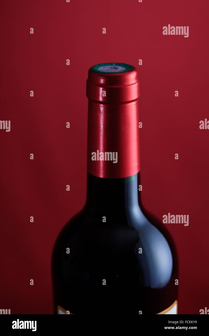 A single bottle of French Bordeaux wine on a crimson base and backdrop