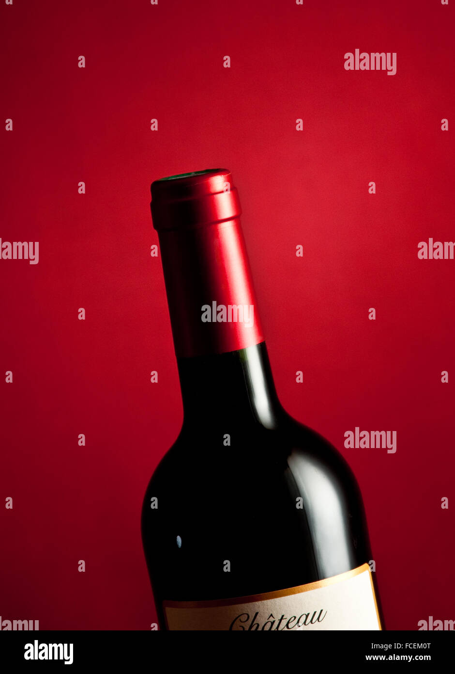 A single bottle of French Bordeaux wine on a crimson base and backdrop. Stock Photo