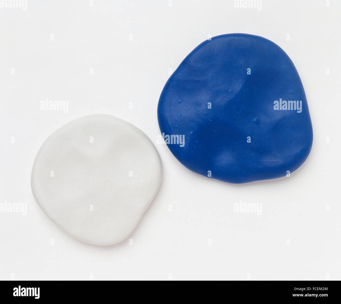 Two flat round pieces of white and blue polymer clay Stock Photo