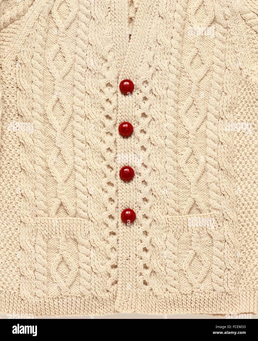 Red leather buttons on knitted beige cardigan, close-up Stock Photo