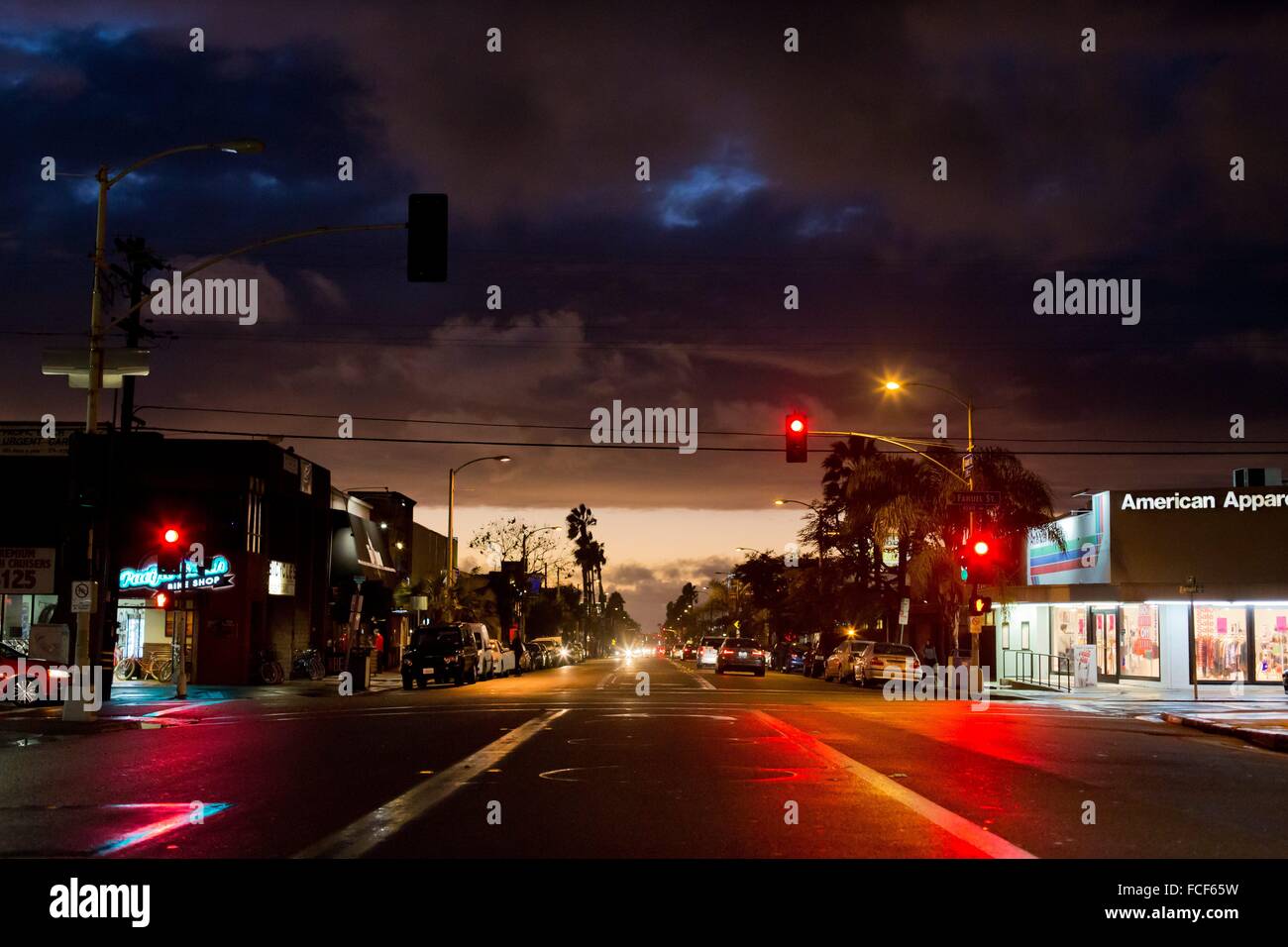 The evening sky and the head lights of cars reflecting in the street wet with rain, at an intersection in Pacific Beach, in January 2016. Stock Photo