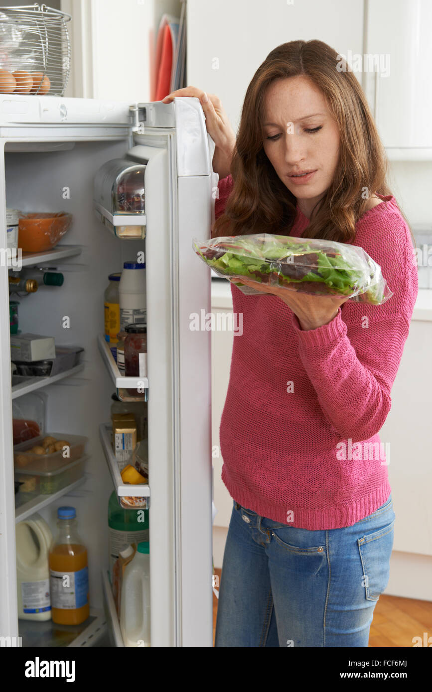 Woman Checking Sell By Date On Salad Bag In Refrigerator Stock Photo