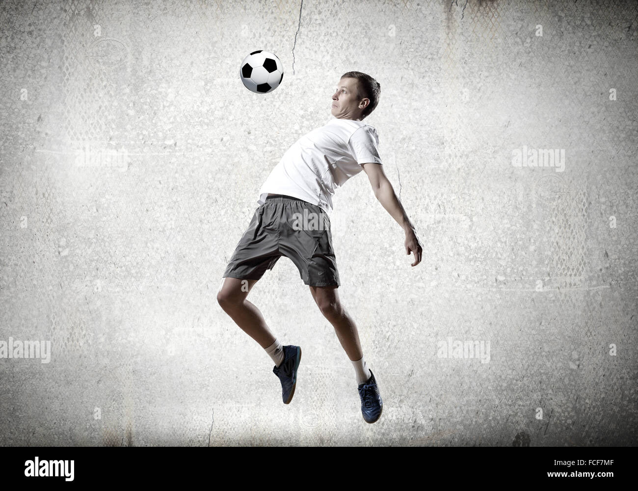 Football player kicking ball against cement background Stock Photo Alamy