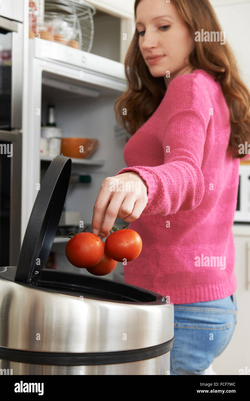 Woman Throwing Away Out Of Date Food In Refrigerator Stock Photo